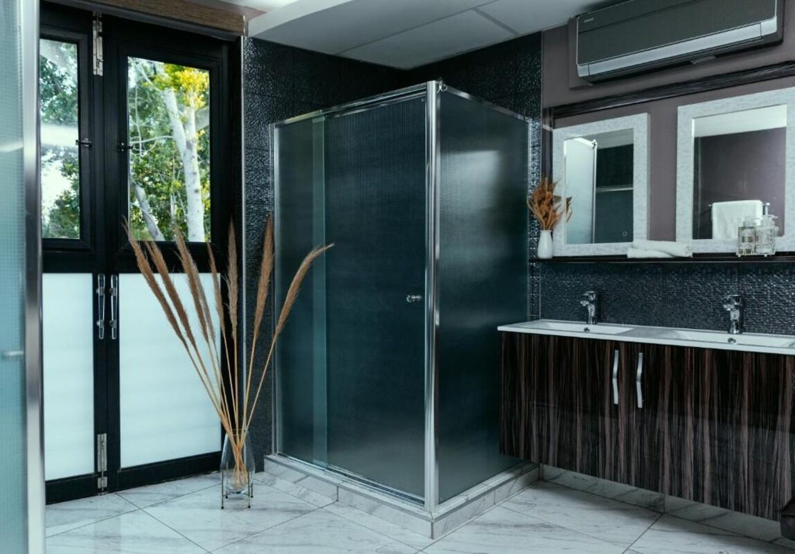 A modern bathroom with a glass shower enclosure, a dark wood vanity, and a large mirror above the sink.