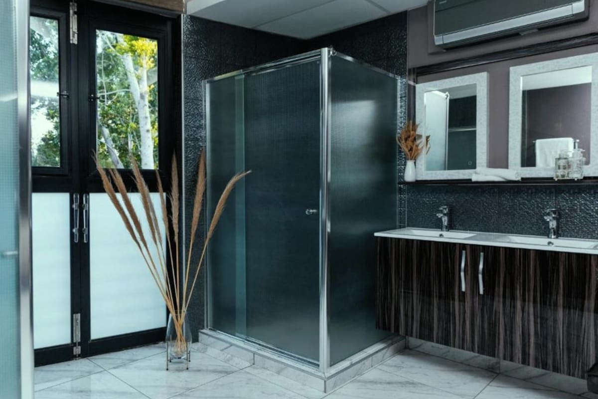 A modern bathroom with a glass shower enclosure, a dark wood vanity, and a large mirror above the sink.