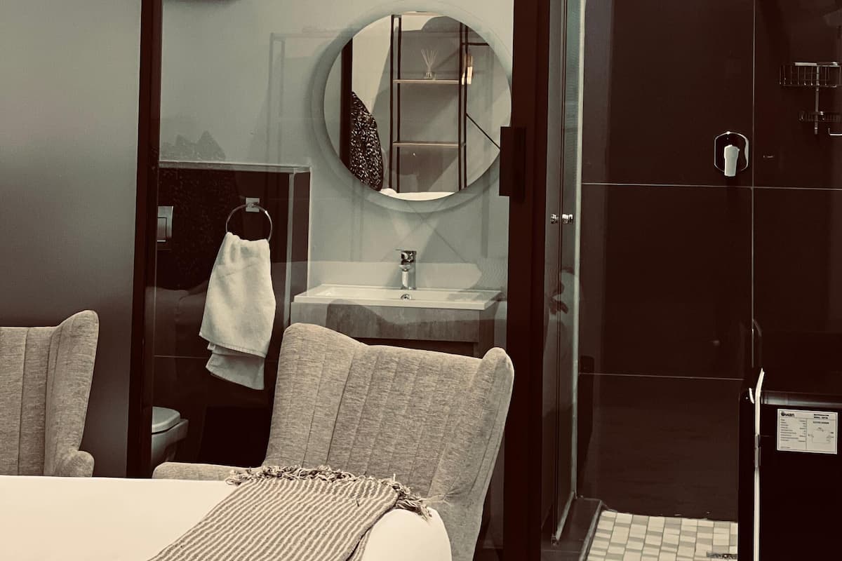 A modern bathroom with a round mirror, a sink, and a shower area.