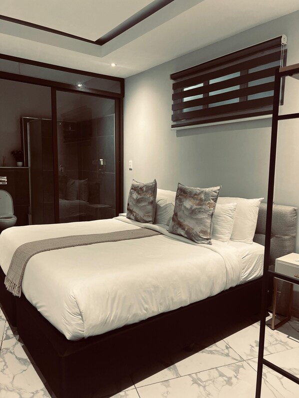 A modern bedroom with a large bed, a walk-in closet, and a built-in shower. - Monte La Vue Boutique Hotel (Sandton)