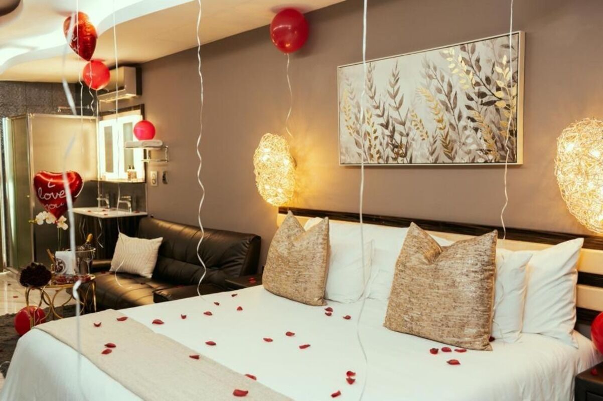 A hotel room with a bed, a sofa, a painting on the wall, and a chandelier.