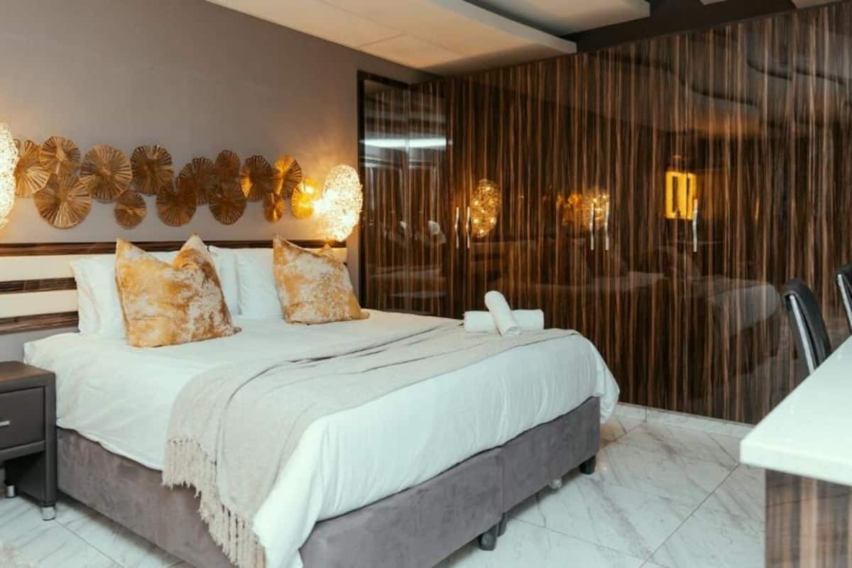 A modern bedroom with a large bed, a bedside table, a nightstand, and a wall-mounted light fixture.