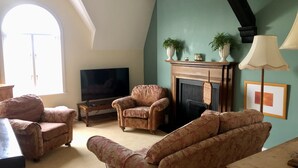 A living room with a fireplace, two armchairs, a sofa, a television, and a lamp. - Charming 2-bed Apartment in Waterloo, Liverpool (Liverpool)