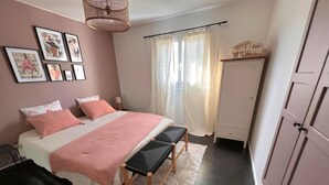 Une chambre à coucher comprenant un lit, des tables de chevet, un banc, une armoire et des œuvres d’art encadrées accrochées au mur.