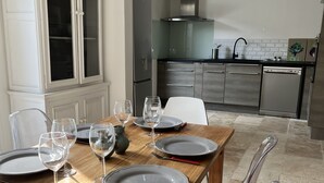 Un coin repas avec une table en bois, dressée pour quatre personnes, entourée de chaises.
