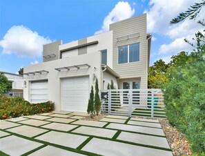 Uma casa moderna de dois andares com garagem, entrada por portão e gramado bem cuidado.