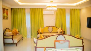 Una habitación de hotel con cama, sofá, mesa de comedor y televisor.