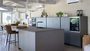 A modern kitchen with a central island, pendant lights, and a built-in refrigerator.