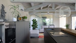 A modern kitchen with a built-in oven, a large island with a sink, and a dining area with a sofa and a coffee table.