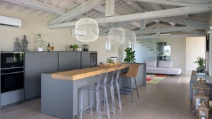 A modern kitchen with a wooden island, bar stools, and pendant lights.