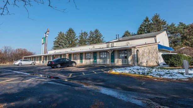 A motel with a row of rooms, a parking lot, and a flagpole. - Hotel Wadsworth OH I-76 (Wadsworth)