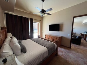 A hotel room with a bed, a ceiling fan, a TV, a wooden dresser, and a view of the outside. - Cabrillo 103 ground floor 2, we also own Cabrillo 102,104 and 106  (Puerto Peñasco)