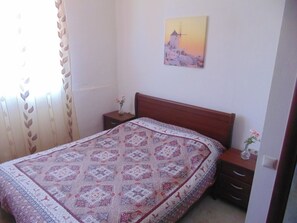 Une chambre à coucher avec un lit en bois, une table de chevet et une commode, ainsi qu’un tableau accroché au mur.