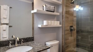 Ein modernes Badezimmer mit einem Waschbecken aus Granit, einer Toilette und einer Duschkabine.