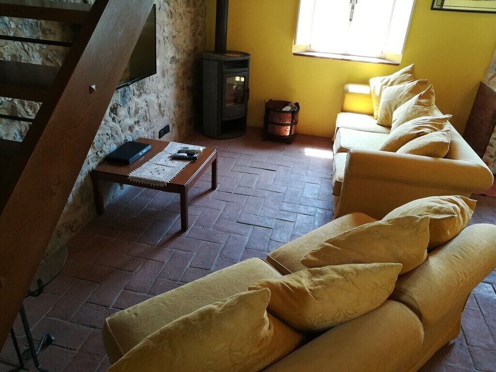 Uma sala de estar acolhedora com um sofá, uma mesa com um livro e um bloco de notas, um pequeno aquecedor e uma janela com luz do sol.