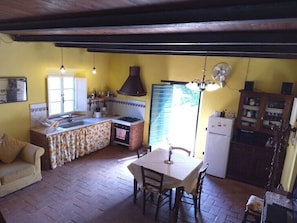 A compact kitchen with a dining table, chairs, and a sofa.