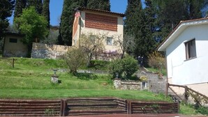 Ein Poolbereich mit Holzzaun, Steinmauer und Gebäude mit Ziegeldach.