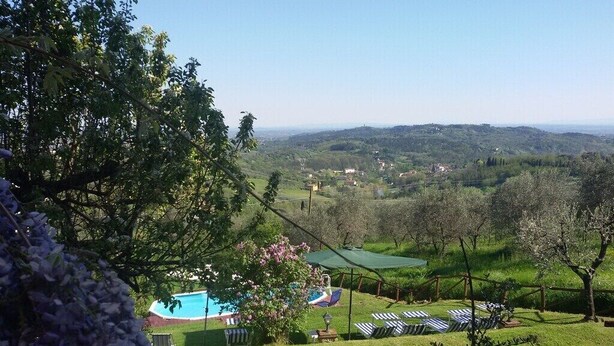 Ein Poolbereich mit Liegestühlen und Blick auf eine hügelige Landschaft.
