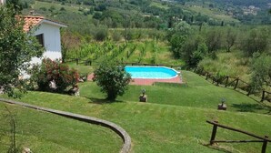 Ein Pool, umgeben von einer Rasenfläche, mit Blick auf eine hügelige Landschaft.