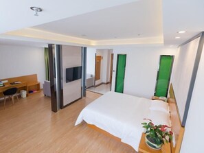 Een moderne hotelkamer met een groot bed, een bureau met stoel, een televisie en een groene deur.