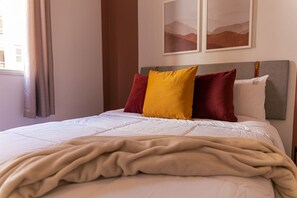 Relax in a serene space with a comfortable bed, adorned with pillows and artwork.