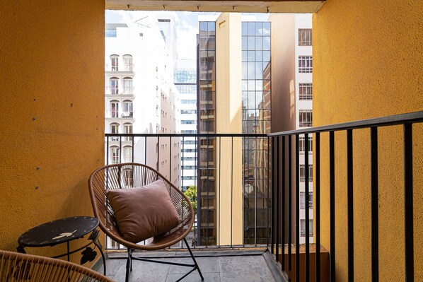 Enjoy the city view from this balcony with a wicker chair and small table.