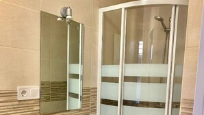 A bathroom with a white sink, a mirror, and a glass shower enclosure.