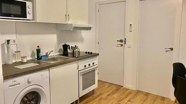 A compact kitchen with a microwave, stove, oven, and washing machine.
