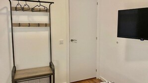 A room with a coat rack, a door, and a mounted television.