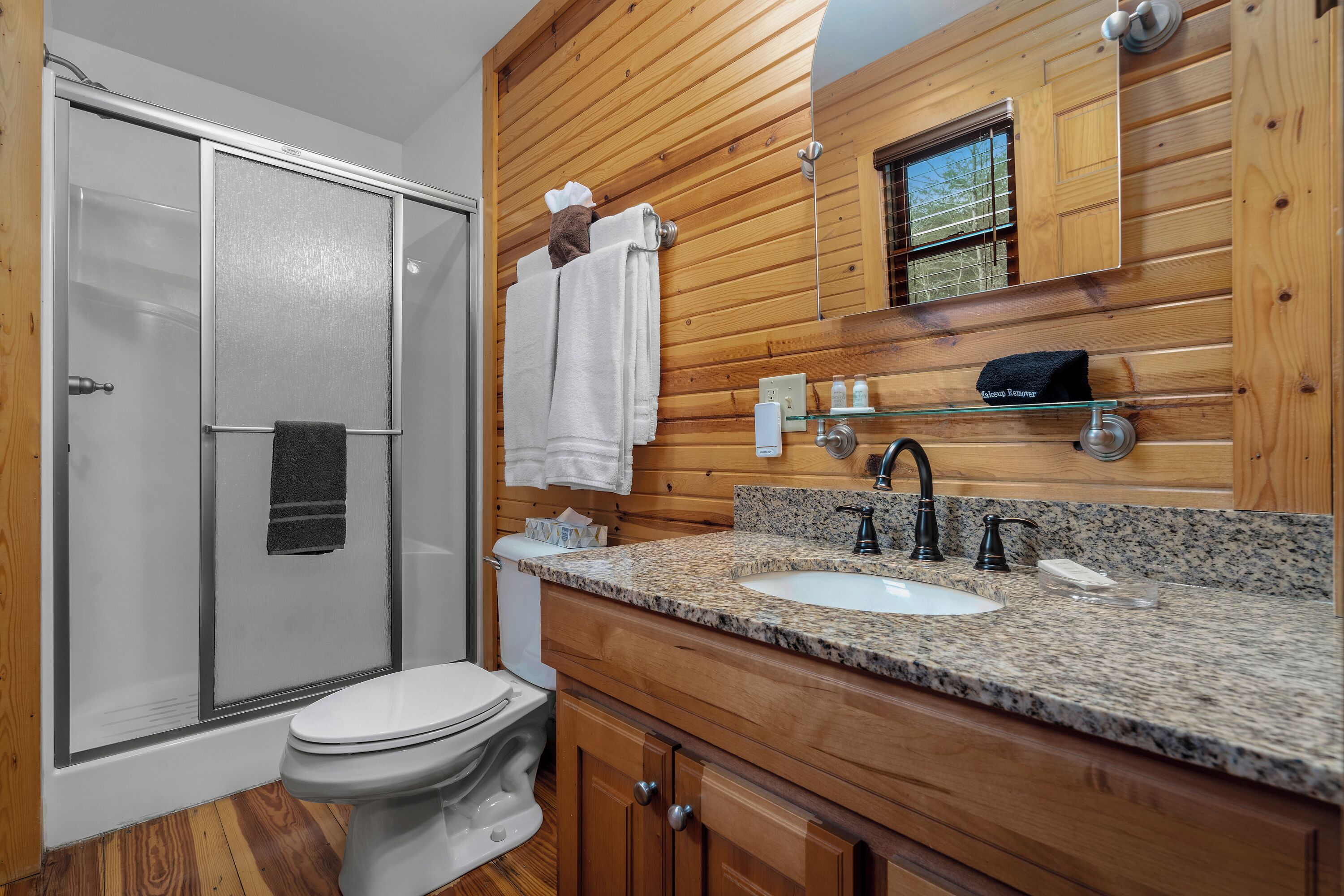 Ein Badezimmer mit Dusche, Toilette, Waschtisch und Holzvertäfelung.