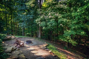 A forested area with a fire pit and wooden chairs. - Cherry Ridge Retreat (New Plymouth)