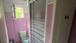 Et badeværelse med toilet, brusebad og et vindue.