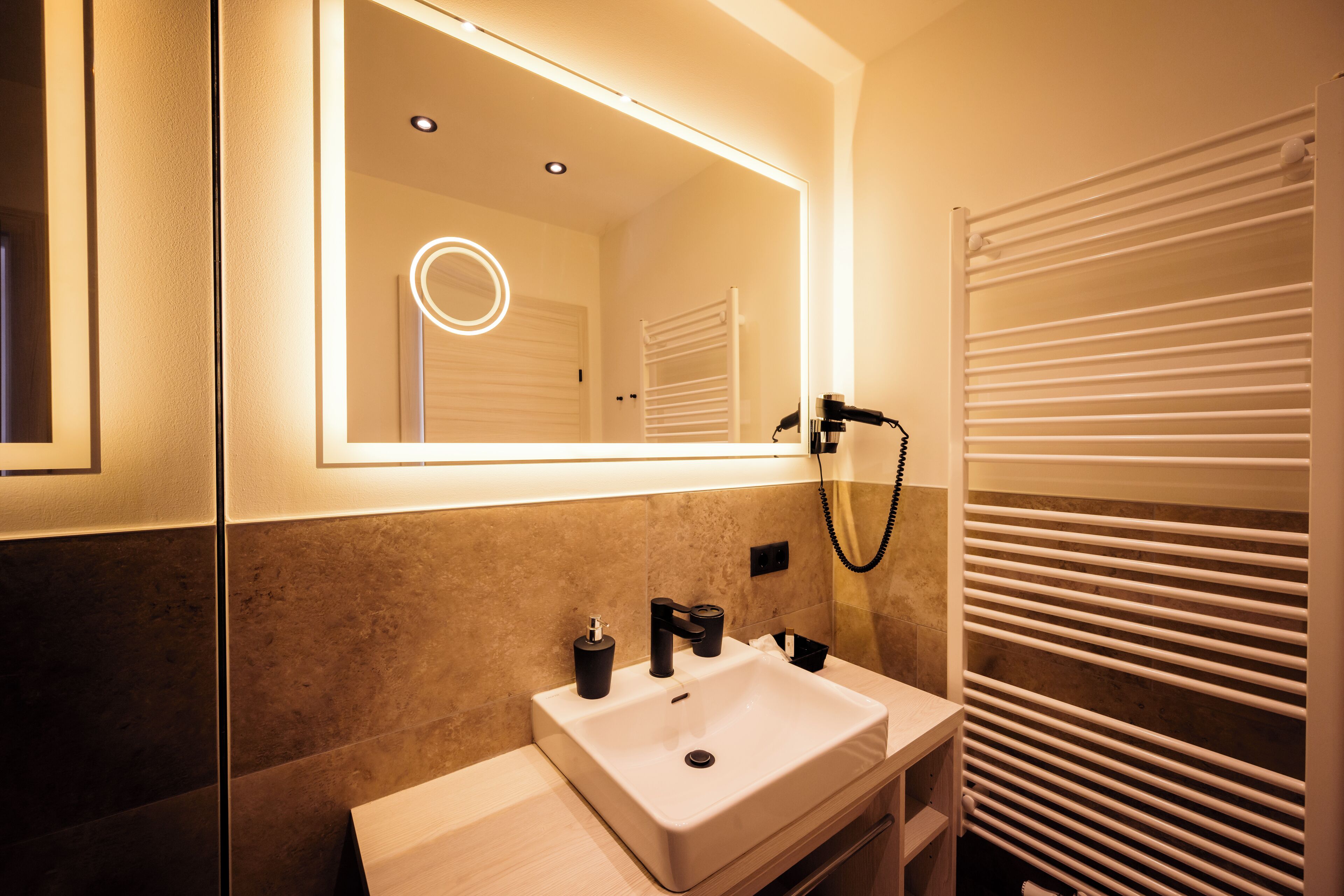 A modern bathroom with a large mirror, a sink, and a towel rack.