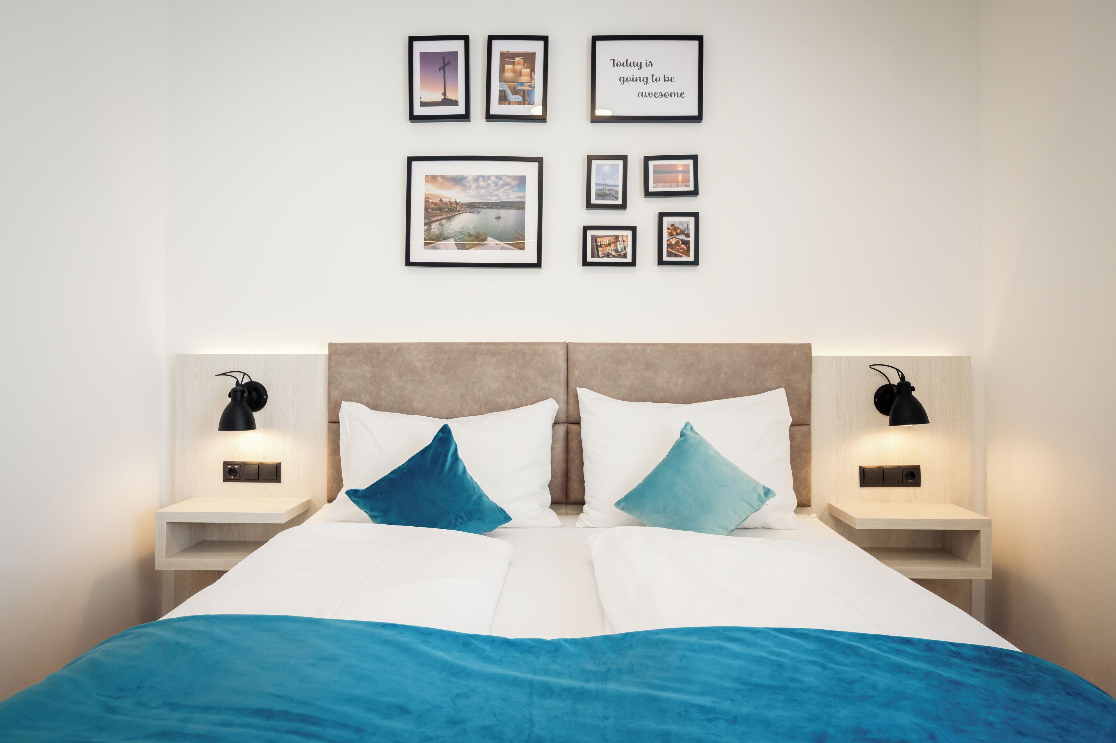 A hotel room with a bed, two bedside tables, a nightstand, and a wall with framed pictures.