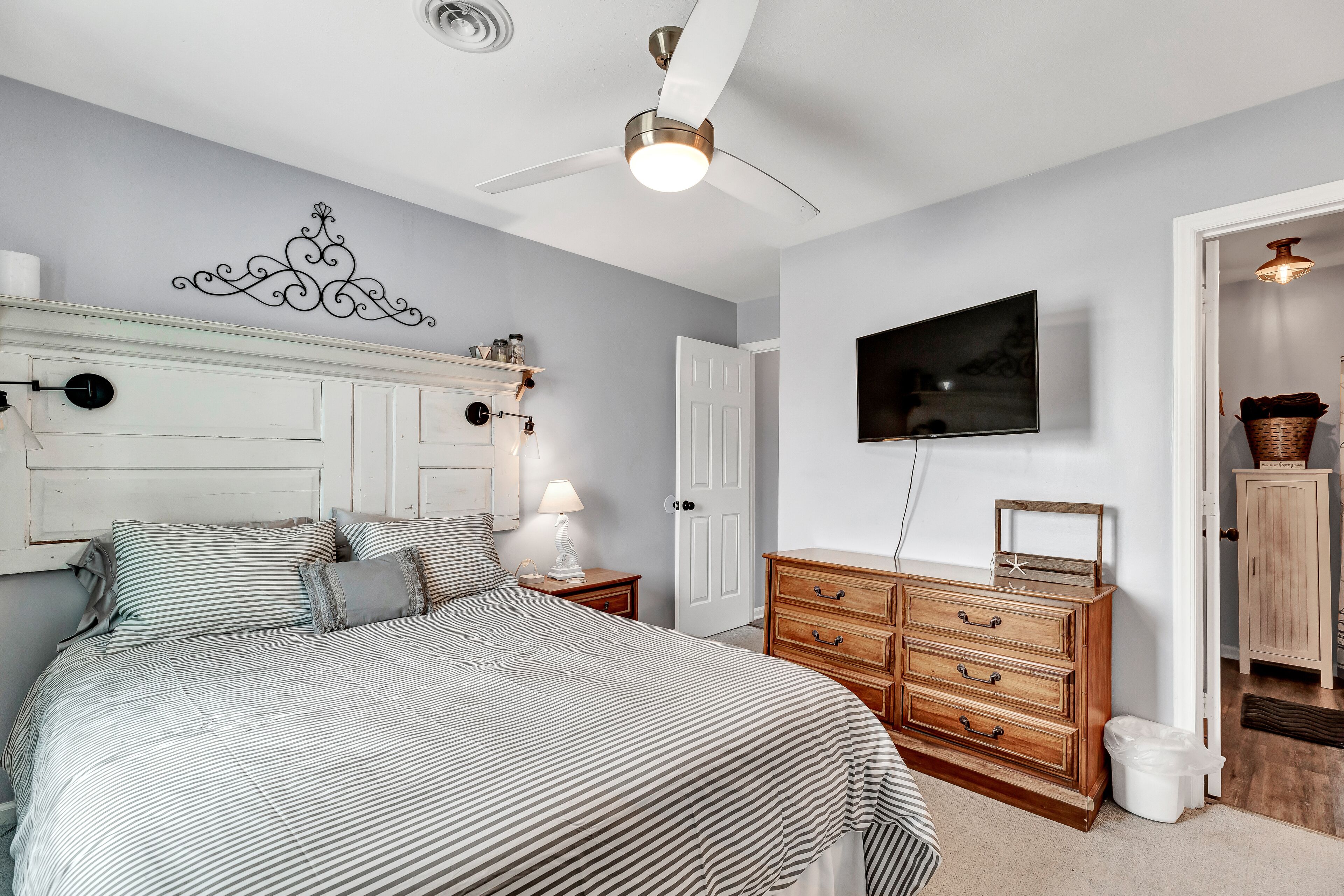Un dormitorio con cama, cómoda, televisor y ventilador de techo.