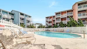 A pool area with lounge chairs and a white picket fence. - Beach, Please! (Carolina Beach)