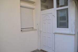 The building features a traditional door with a central panel and two smaller panels on either side, set against a white exterior.