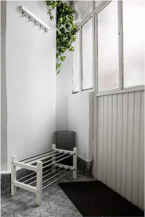 A cozy space with a bench and trash can, adjacent to a window with frosted glass.