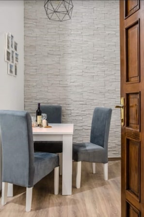Enjoy meals in this stylish dining area with a table and two chairs, a unique light fixture, and a textured wall.