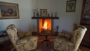 Ein gemütliches Zimmer mit Kamin, floralen Sesseln und gerahmten Kunstwerken.