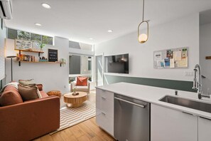 Una cocina moderna con lavavajillas integrado, un comedor con mesa redonda y una sala de estar con sofá.