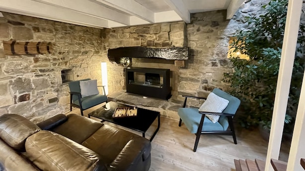 A cozy living room with a stone wall, a fireplace, a leather sofa, and a coffee table.