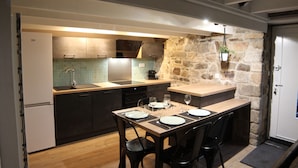 A modern kitchen with a stone accent wall, a dining area with a table set for four, and a built-in oven.