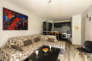 Un soggiorno con un divano decorato, un tavolino da caffè con un croissant e un quadro appeso al muro.