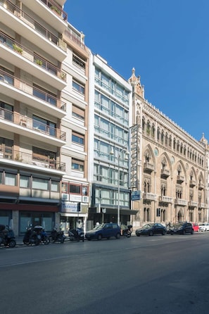 A multi-story building with balconies, a modern glass facade, and a historic building with ornate architecture. - Hotel Executive Business (Bari)