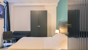 Hotellihuone, jossa on sänky, työpöytä, tuoli, vaatekaappi ja televisio.