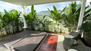 A covered patio area with a massage table, wicker furniture, and lush tropical plants. - Kamala Garden View villa by Lofty  (Kamala)