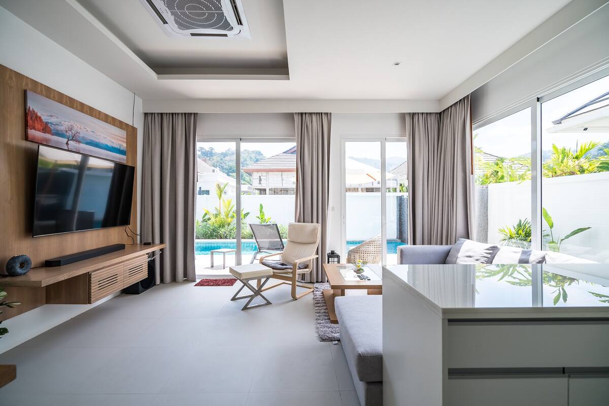 Una sala de estar moderna con televisor de pantalla plana, un espacio de descanso cómodo y vistas al exterior.