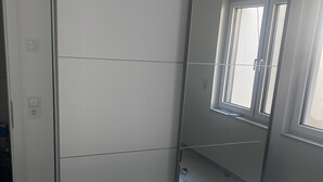 A bedroom with a bed, a wardrobe, and a window.