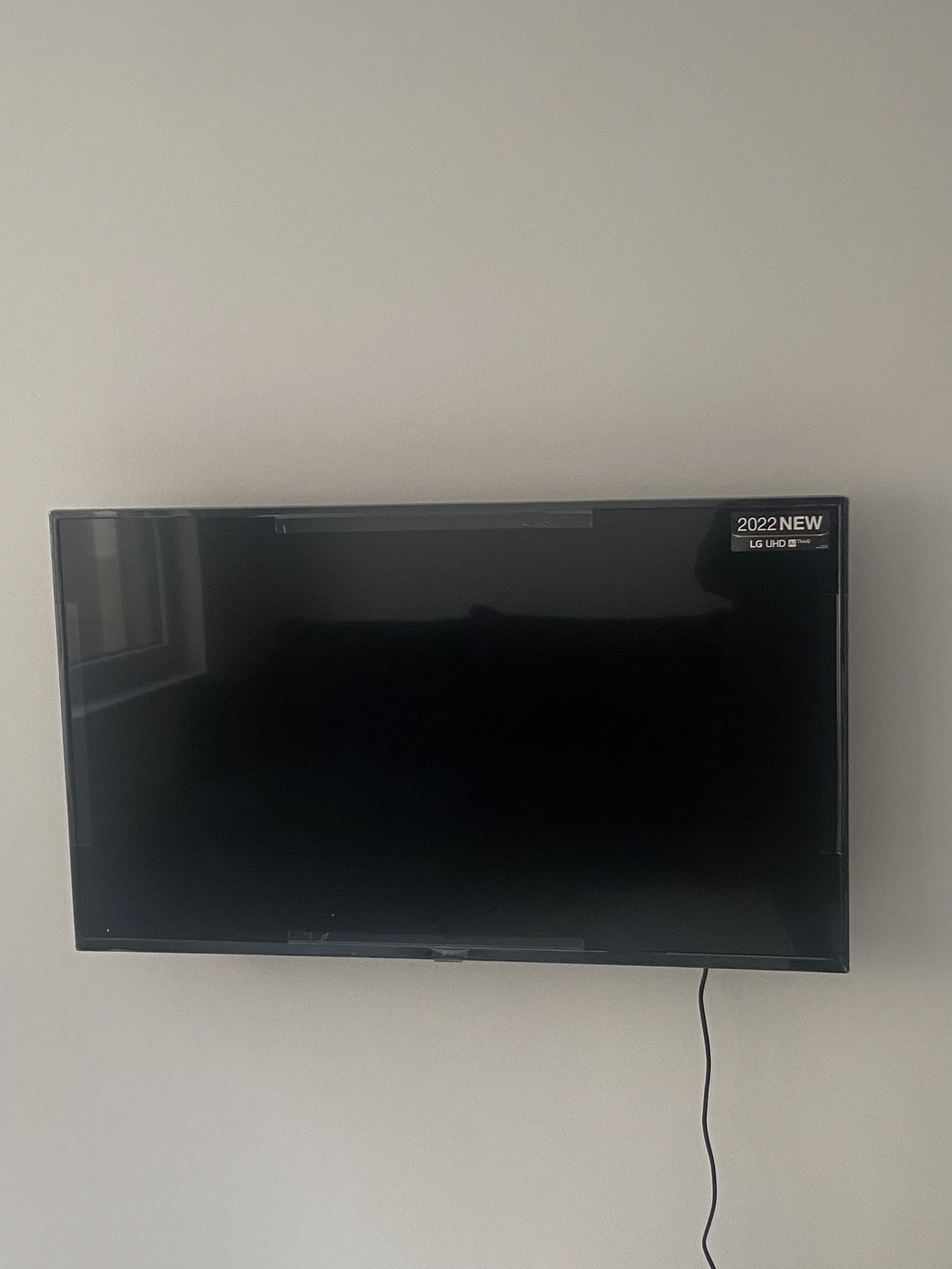 A flat-screen TV mounted on a wall with a visible power cord.